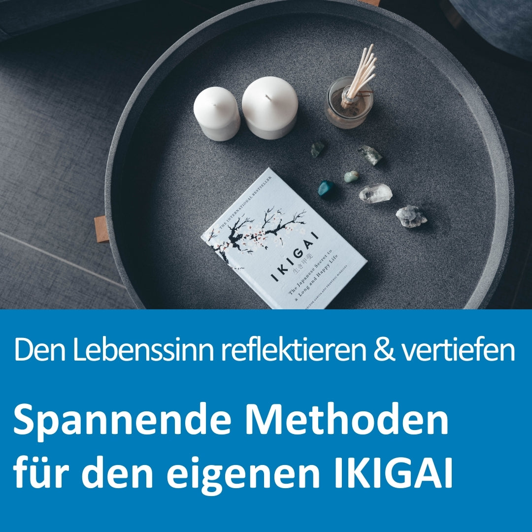 Auf einem runden, dunklen Tablett liegen zwei weiße Kerzen, ein Glas mit Duftstäbchen, verschiedene kleine Edelsteine und ein Buch mit dem Titel „IKIGAI – The Japanese Secret to a Long and Happy Life“. Die Szene vermittelt Achtsamkeit und spirituelle Reflexion. Im unteren Bildbereich steht der Text: „Den Lebenssinn reflektieren & vertiefen – Spannende Methoden für den eigenen IKIGAI“.
