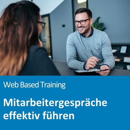 Ein freundlich lächelnder Mann in einem grauen Pullover sitzt mit einem Stift in der Hand an einem Tisch und spricht mit einer Frau, deren Rücken im Vordergrund zu sehen ist. Beide tragen Brillen und befinden sich in einem modernen Büro mit Regalen und Pflanzen im Hintergrund. Der Bildtext lautet: „Web Based Training – Mitarbeitergespräche effektiv führen“.